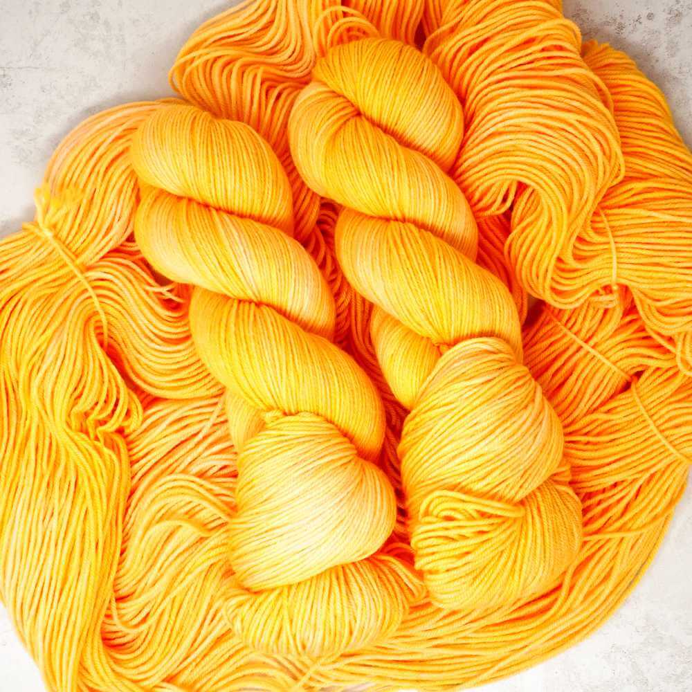Squeeze the Day hand-dyed yarn in vibrant citrus orange and golden yellow, available on a choice of different hand dyed yarn bases | Market Town Yarns