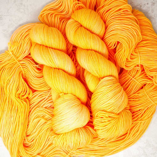 Squeeze the Day hand-dyed yarn in vibrant citrus orange and golden yellow, available on a choice of different hand dyed yarn bases | Market Town Yarns